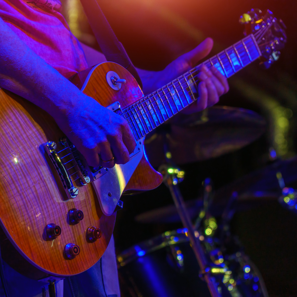 guitarist playing the guitar in the spotlight inside a live music bar