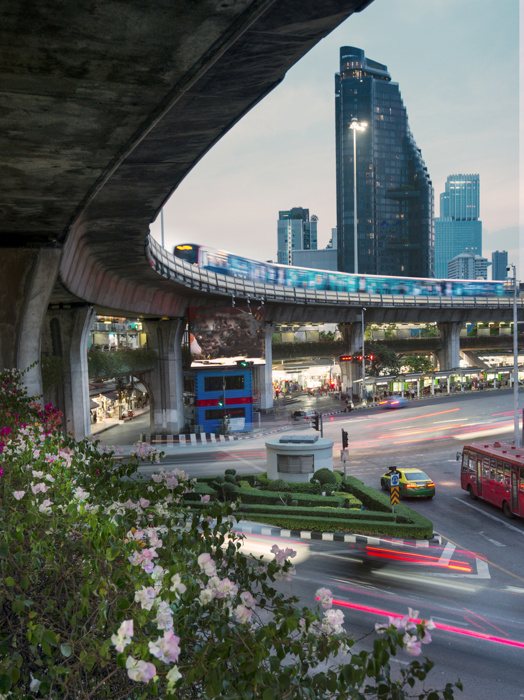 At sunset,during rush hour,the blurred movement of vehicles and a passenger filled train,circulates the busy city center roundabout