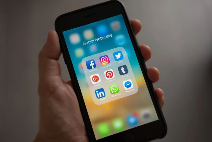 a person holding a phone displaying different social media platforms including Twitter and Instagram