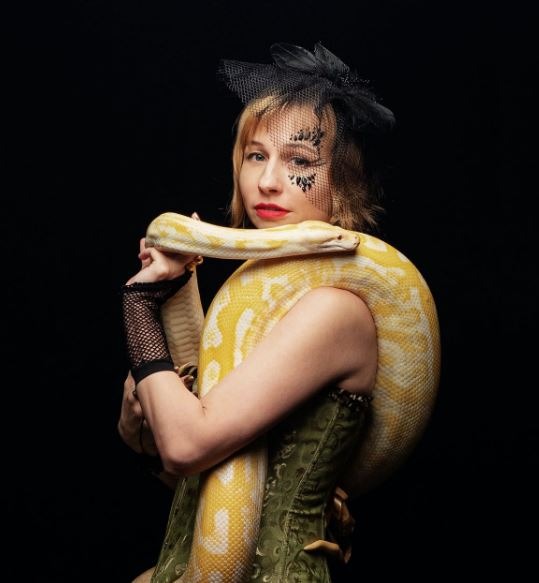 woman with a big live yellow snake on her shoulders