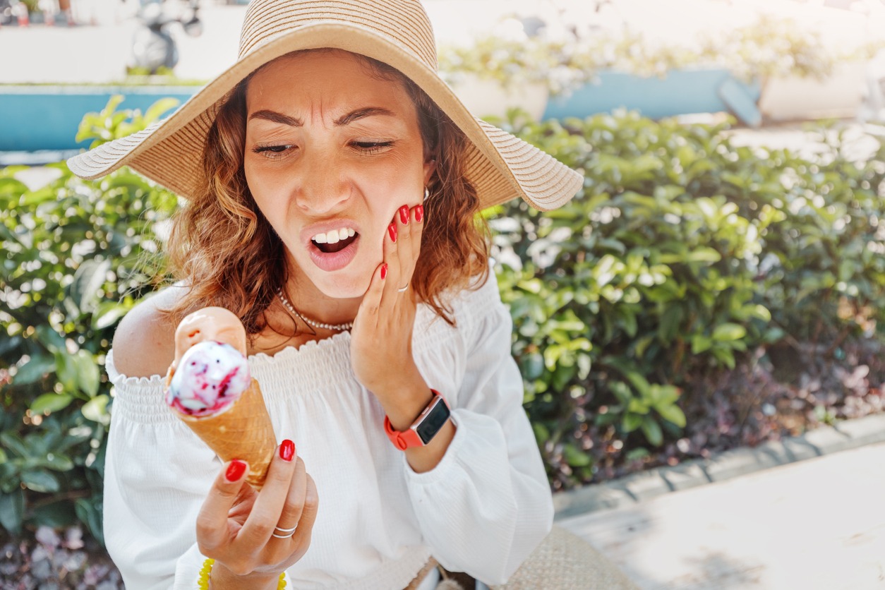 a tourist holding an ice cream, feeling a sharp pain in her teeth